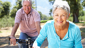 Elderly man and woman riding bicycles.